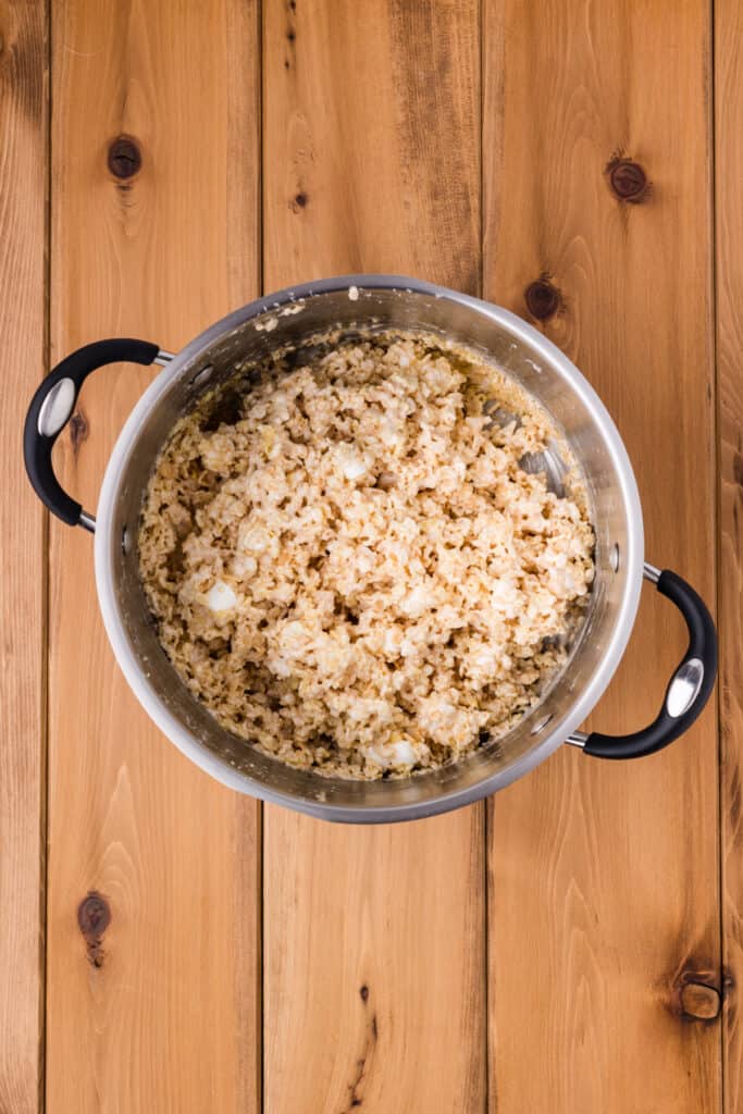crispy rice cereal mixed with melted marshmallow mixture in a saucepan