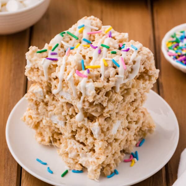 stack of lemon rice crispy treats topped with white drizzle and colorful sprinkles on a white plate