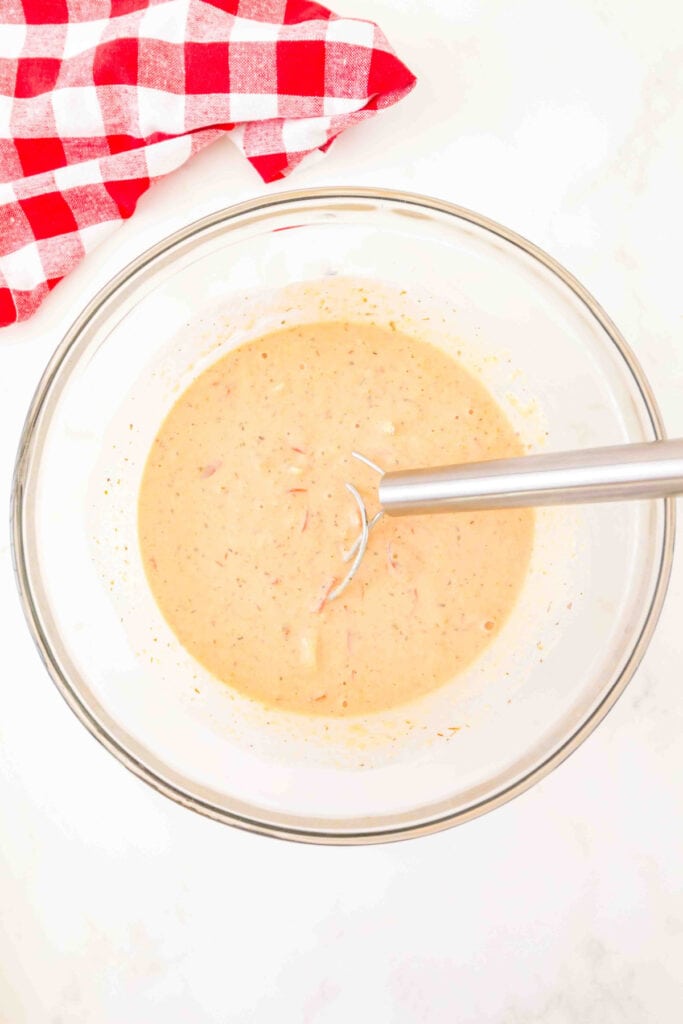 pizza muffin batter mixed together in a bowl with a whisk