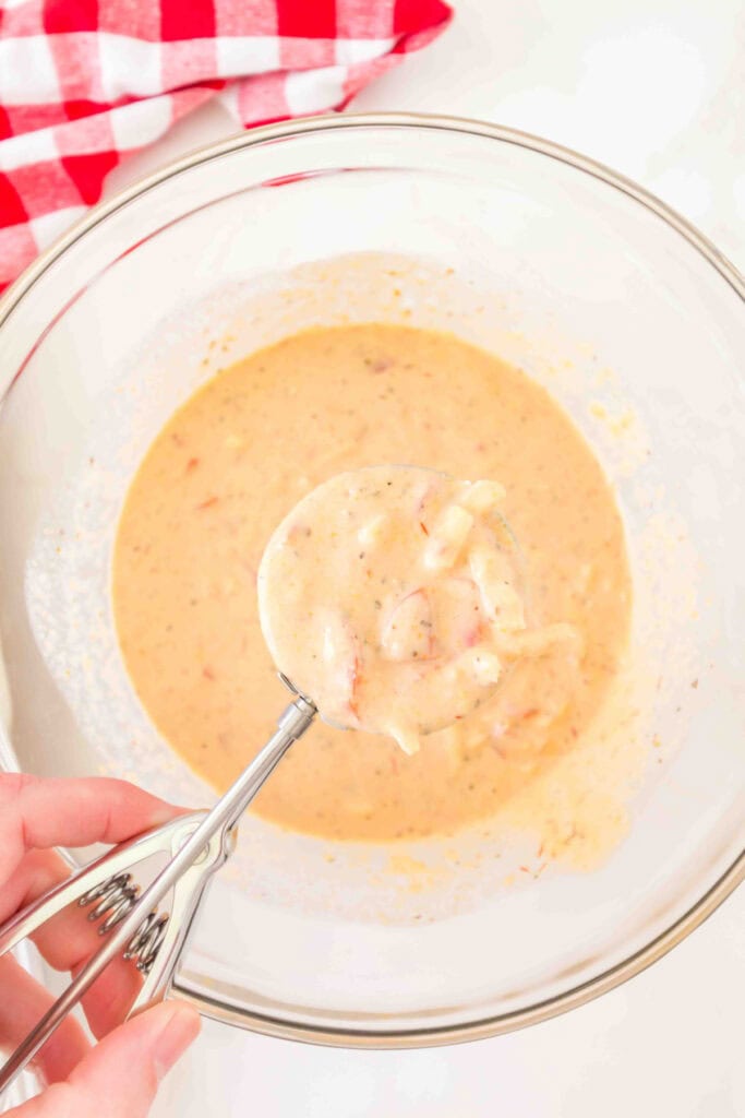 scoop of pizza muffin batter lifted from the bowl with a cookie scoop