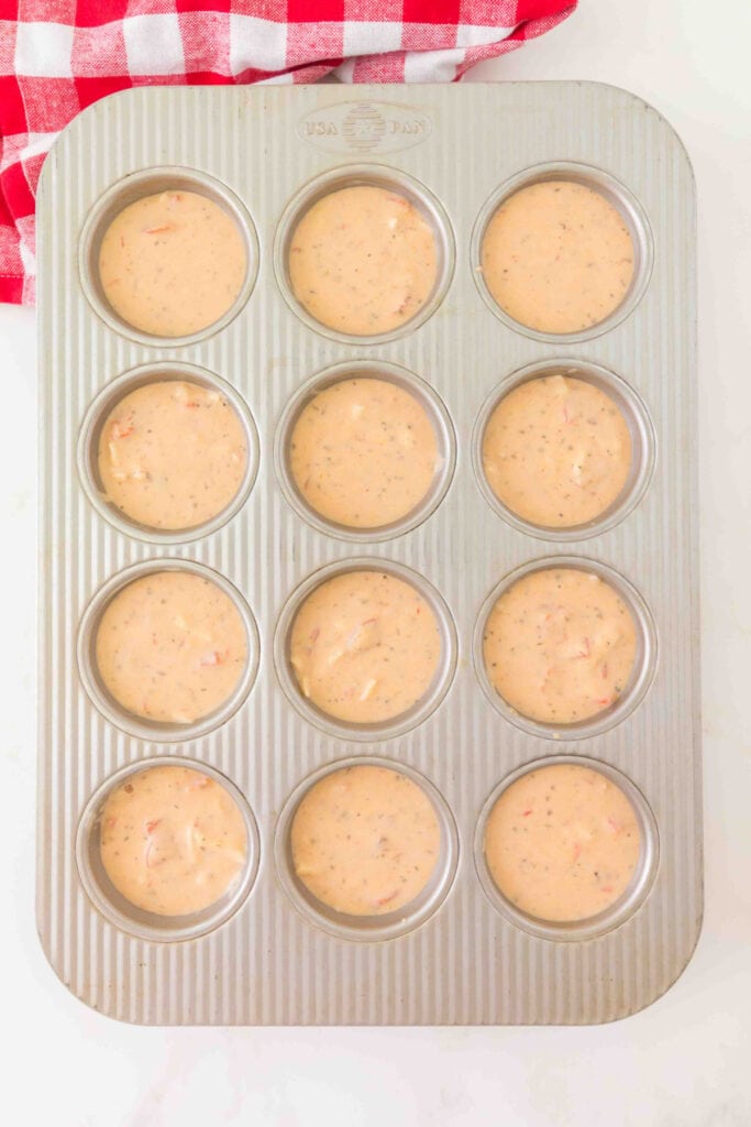 pizza muffin batter portioned into a greased 12-cup muffin pan before baking