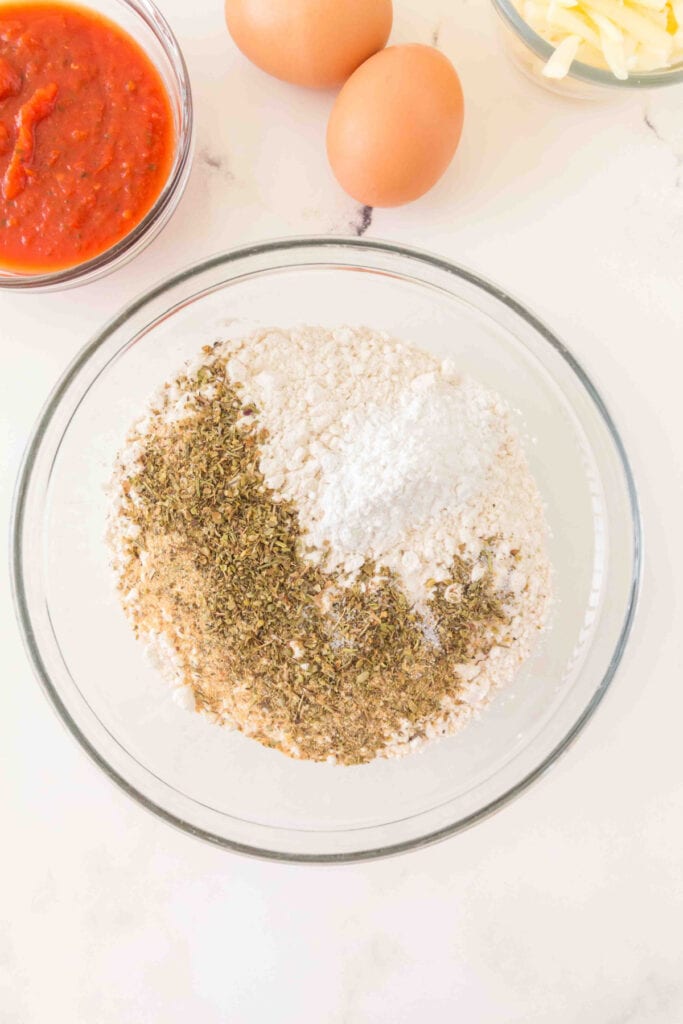 bowl of flour with Italian seasoning, garlic powder, baking powder, and salt added on top