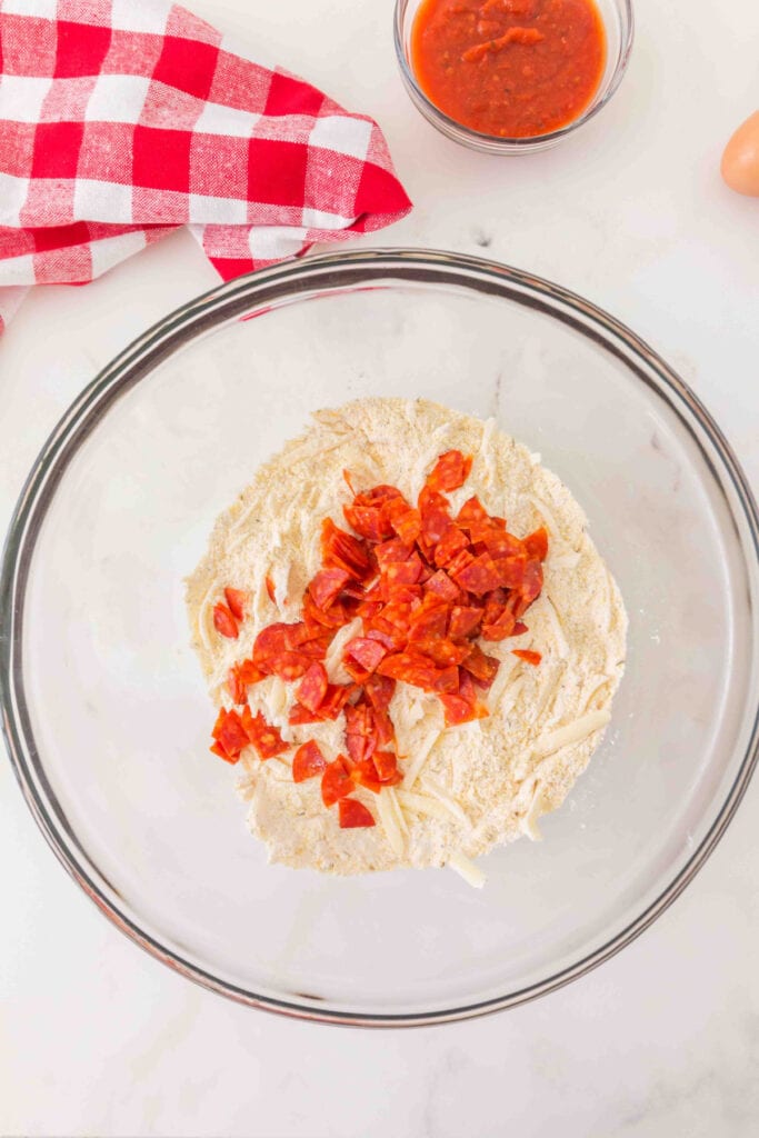 chopped pepperoni added to the flour and cheese mixture in a mixing bowl