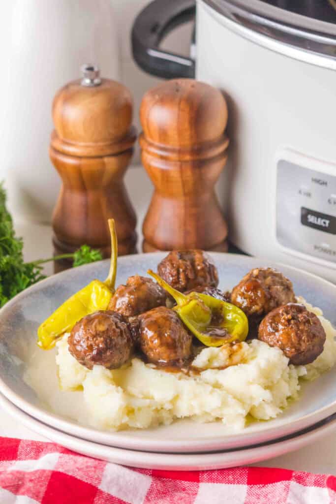 close-up of slow cooker mississippi meatballs on mashed potatoes with pepperoncini peppers