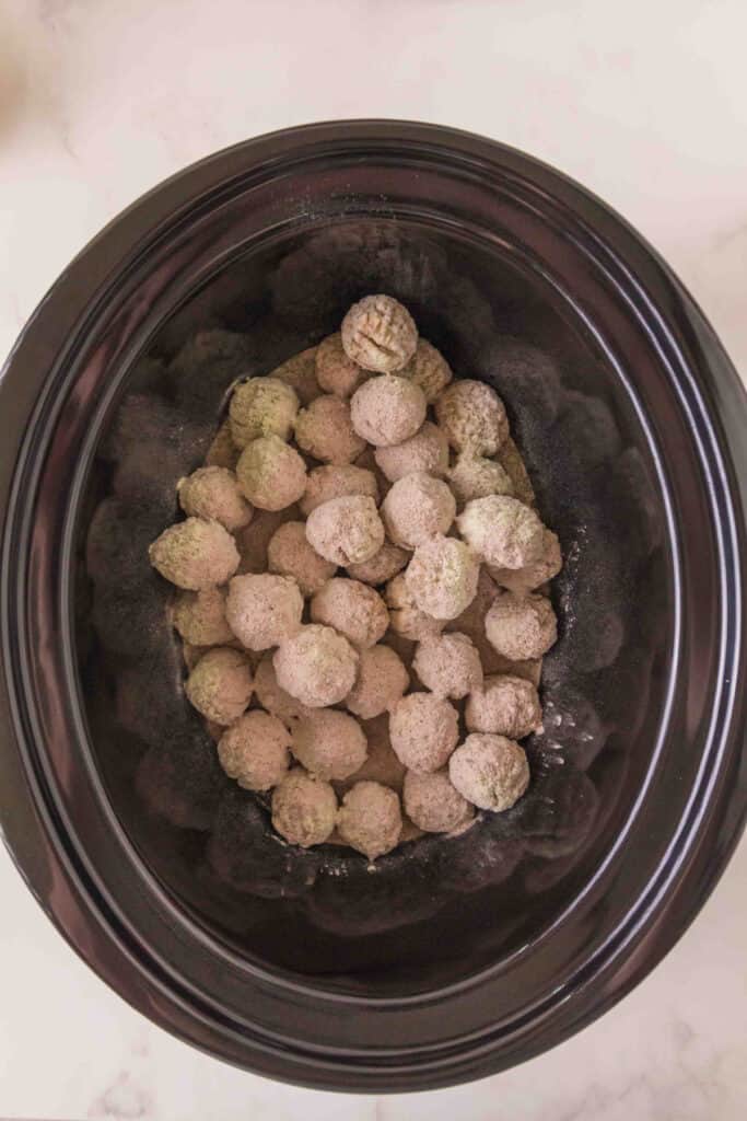 frozen meatballs in a slow cooker sprinkled with ranch seasoning and au jus gravy mix