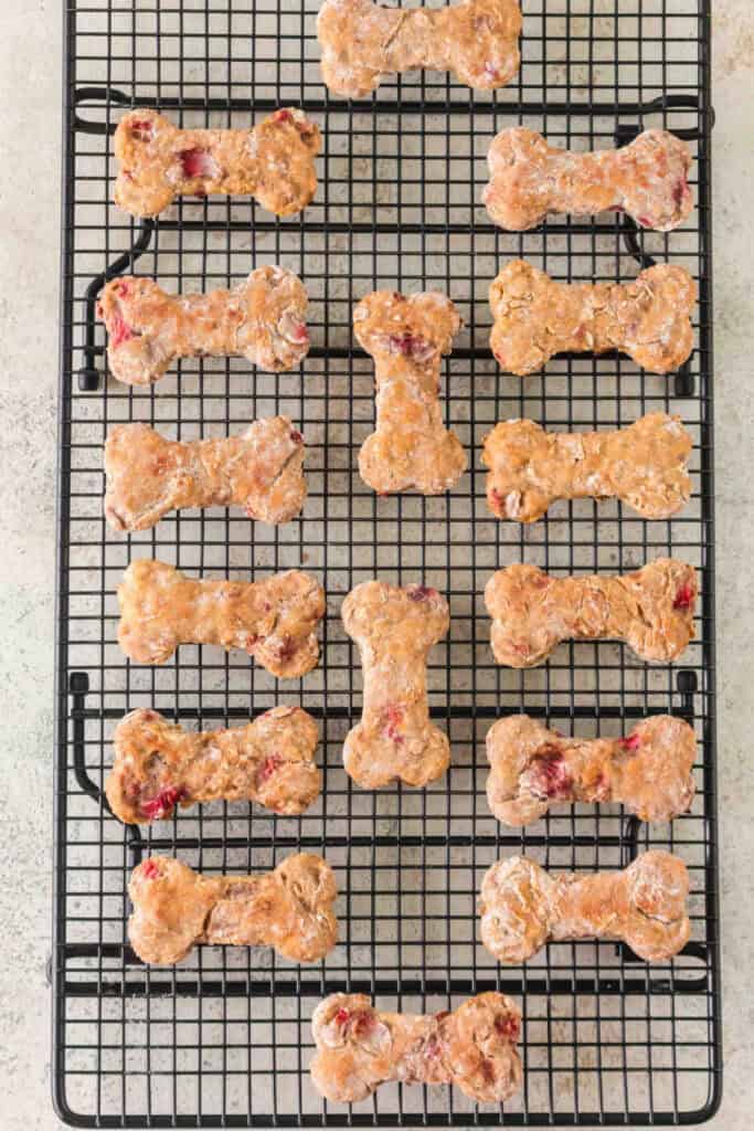 baked strawberry banana dog treats shaped like bones cooling on a wire rack