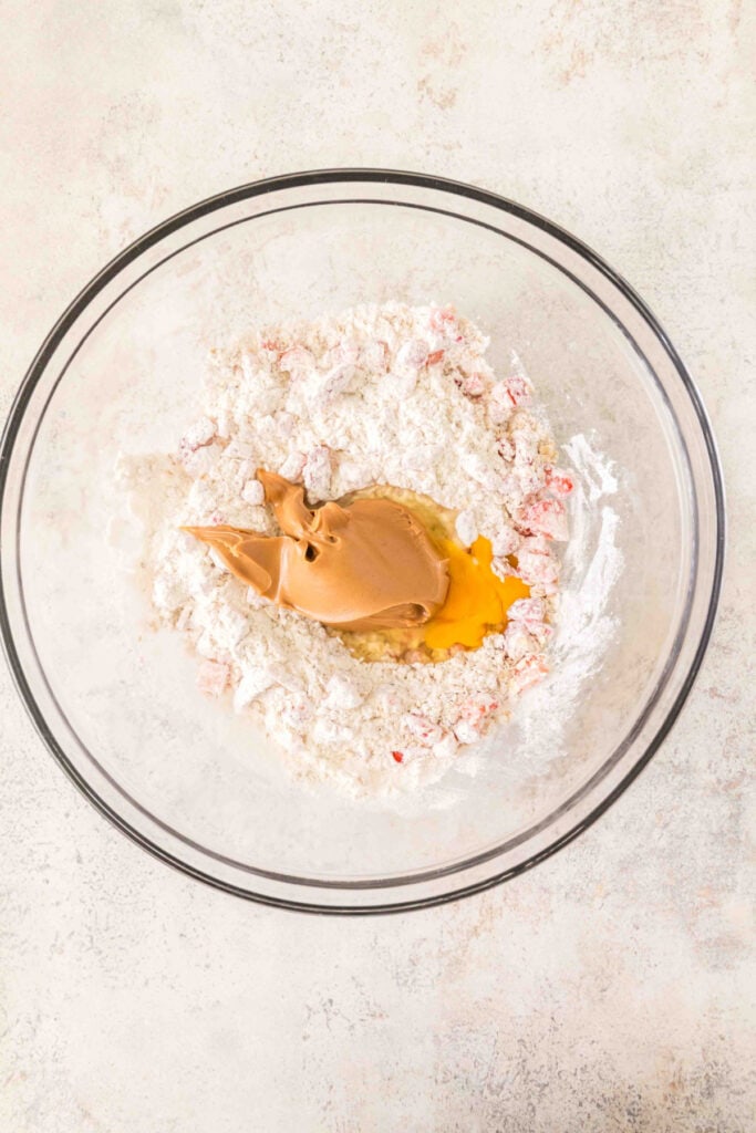 flour mixture with chopped strawberries, egg, and peanut butter in a glass mixing bowl