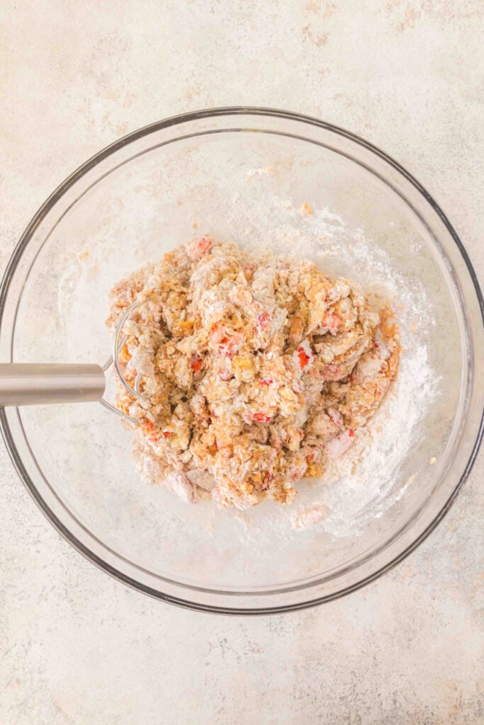 thick dog treat dough with strawberries and oats being mixed in a glass bowl