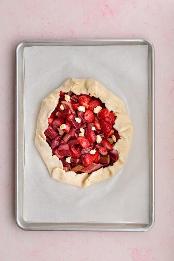 unbaked strawberry rhubarb galette with small pieces of butter scattered over the filling