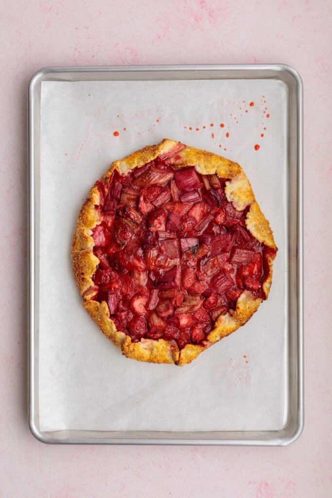 baked strawberry rhubarb galette on a parchment-lined baking sheet with golden crust