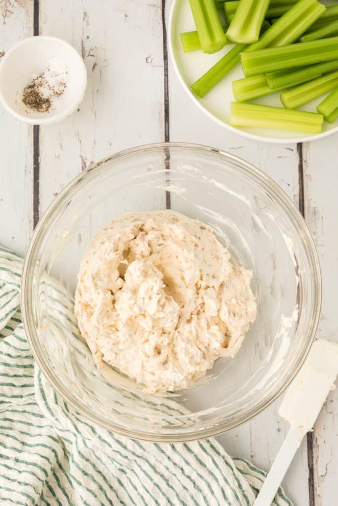 cream cheese mixture fully combined in a glass bowl next to cut celery pieces