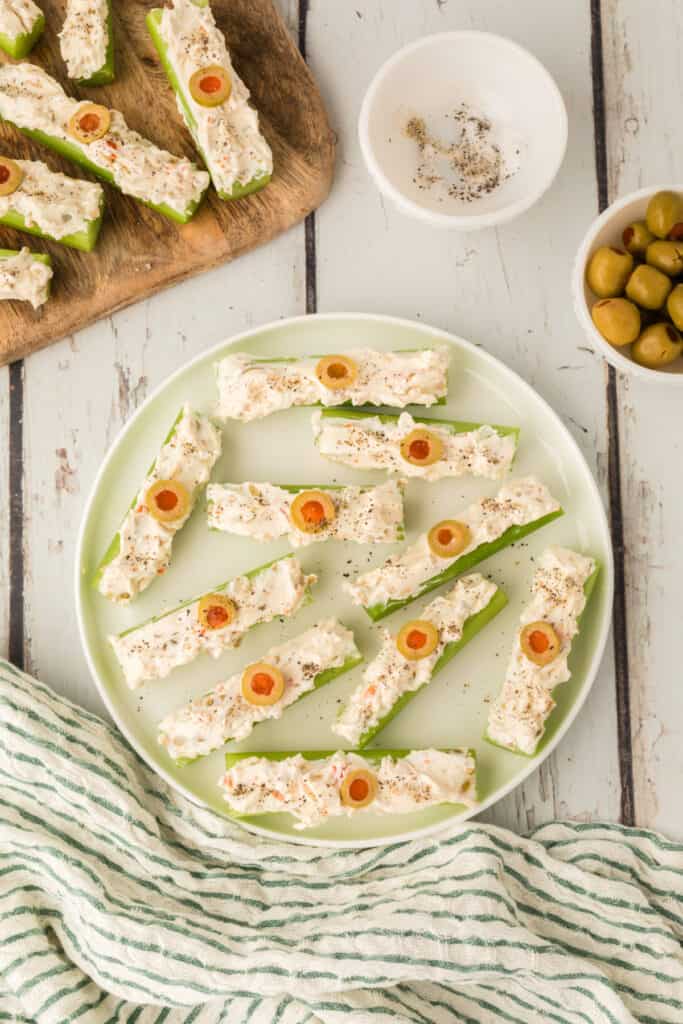 celery sticks filled with cream cheese mixture topped with sliced olives and black pepper