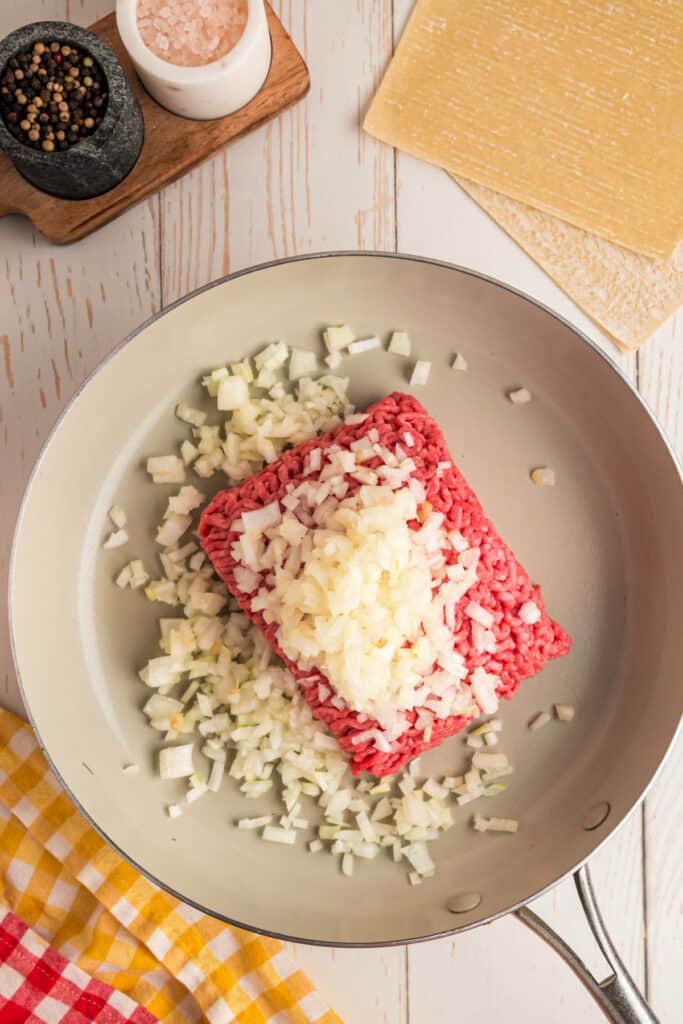 ground beef and diced onion in a skillet before cooking for Big Mac Egg Rolls