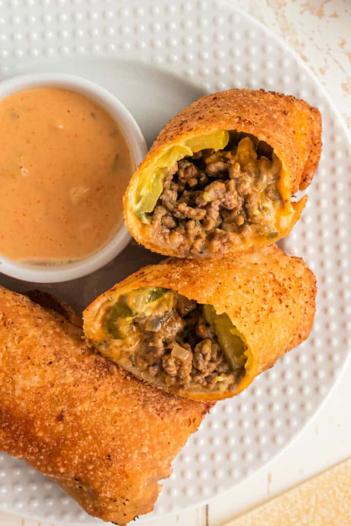 Big Mac Egg Rolls sliced open on plate with dipping sauce on the side