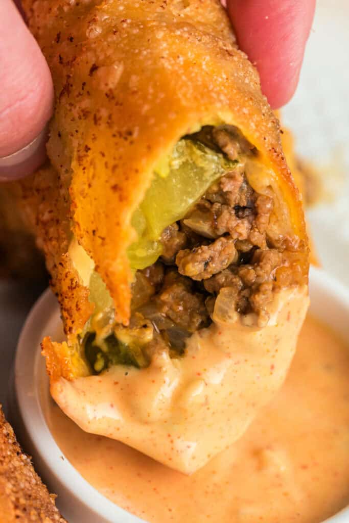 hand holding Big Mac Egg Roll dipped into creamy sauce
