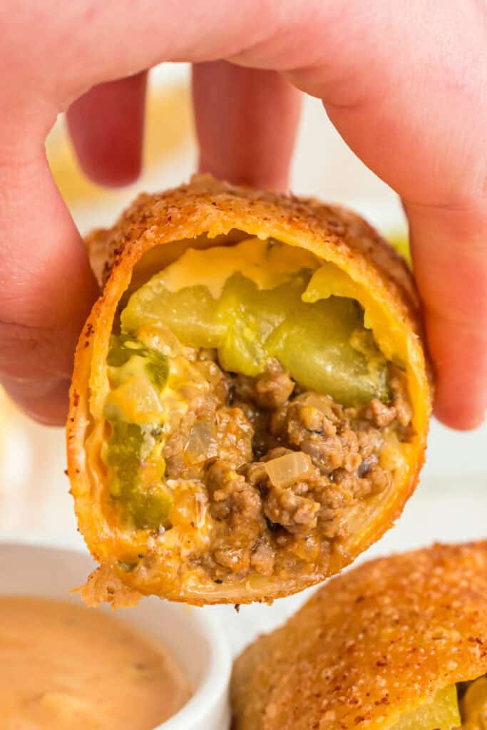 hand holding bitten Big Mac Egg Roll with dipping sauce in background