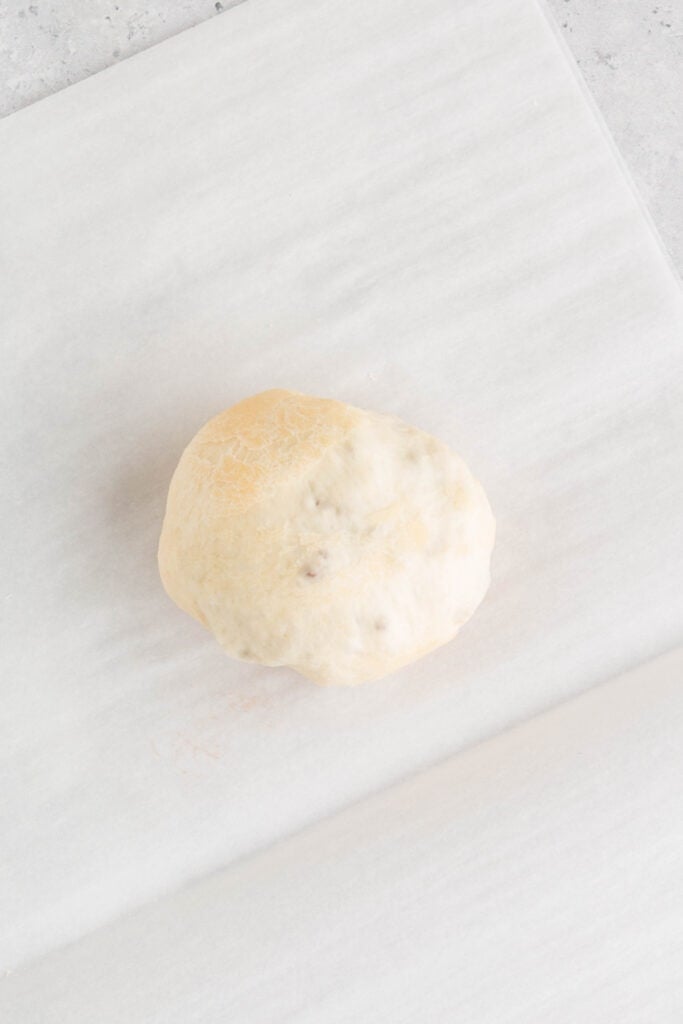 dough wrapped around filling forming a sealed ball on parchment paper