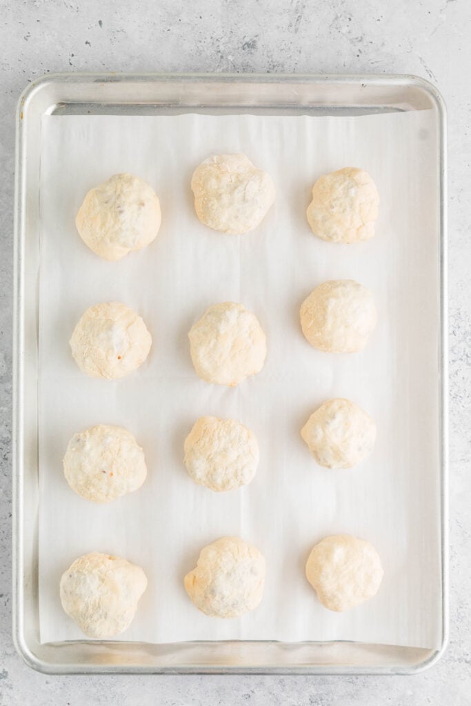 unbaked burger bombs arranged on a parchment-lined baking sheet