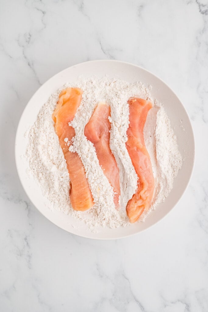 chicken strips coated in flour in a bowl