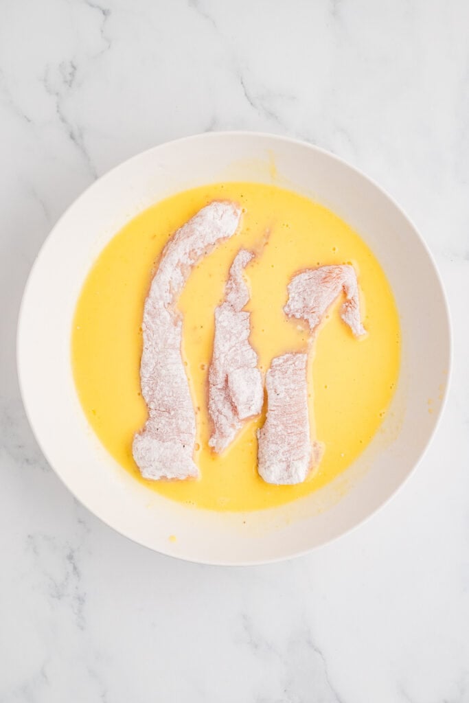 floured chicken strips dipped in egg mixture
