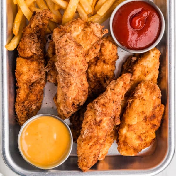 square image of fried chicken strips with fries and dipping sauces