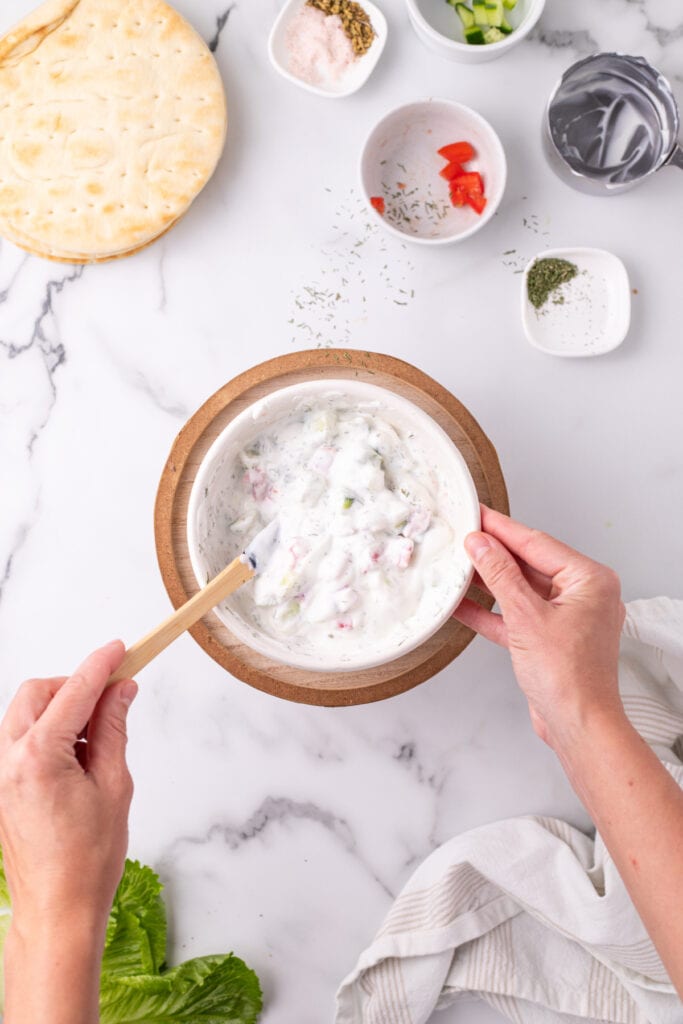 Greek yogurt mixed with chopped cucumber, tomato, and herbs in a bowl