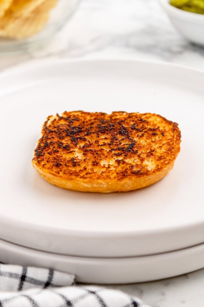 toasted hamburger bun half with a golden brown surface on a white plate