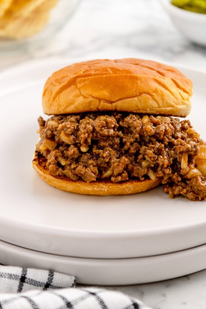 gumbo sloppy joe sandwich with top bun added and filling visible on a white plate