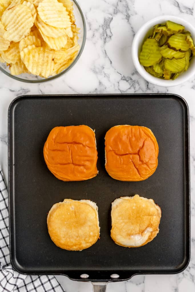 hamburger buns split and toasted on a flat griddle pan