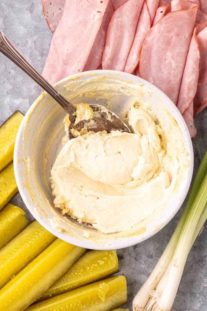 cream cheese mixture fully combined in a bowl with pickles and green onions next to it