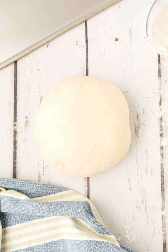smooth ball of homemade onion rolls dough on a lightly floured surface