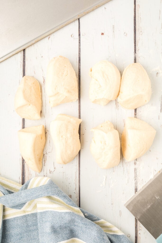 homemade onion rolls dough divided into 8 pieces on a floured surface