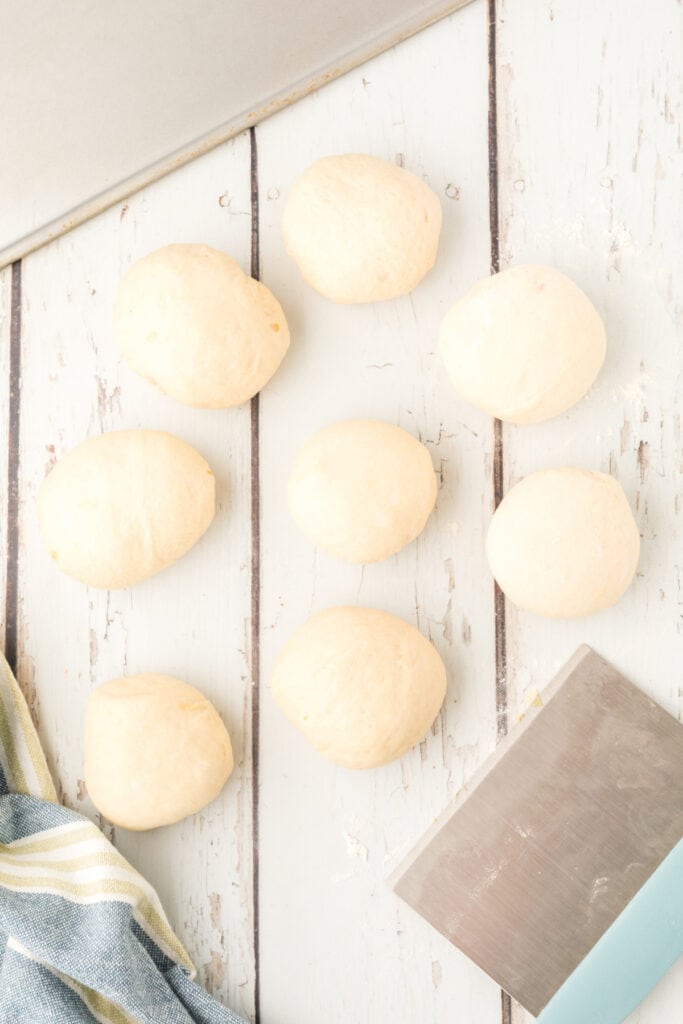 8 dough balls shaped for homemade onion rolls on a floured surface