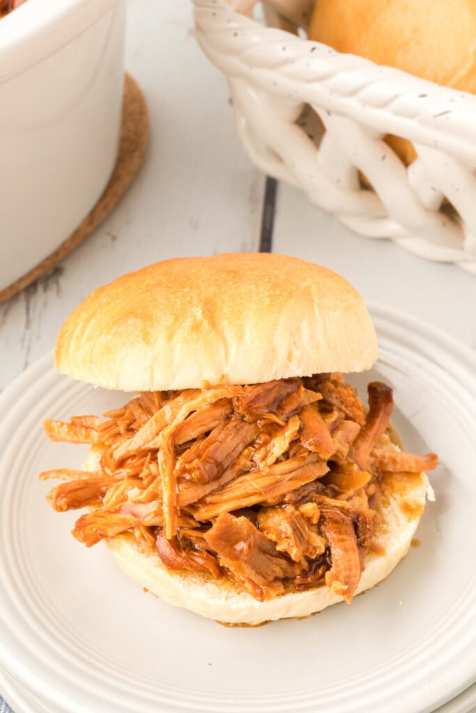 pulled pork sandwich on a homemade onion roll on a white plate