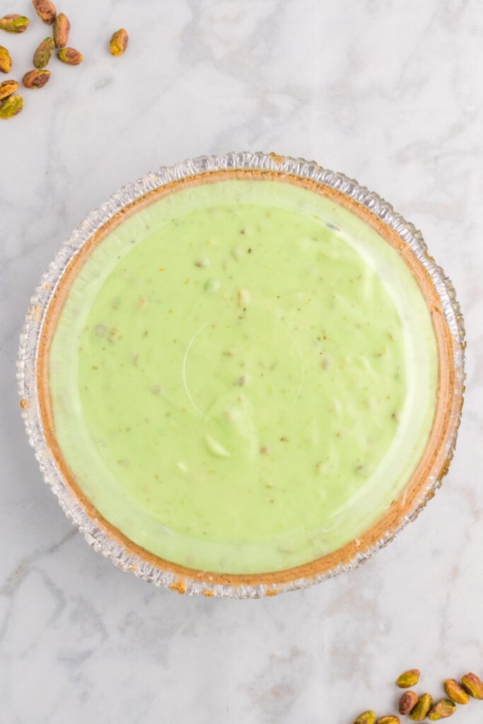 covered smooth pistachio filling in graham cracker crust ready to chill