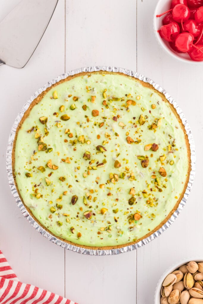 pistachio cream pie topped with chopped pistachios in graham cracker crust