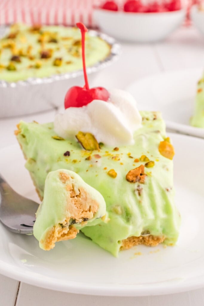 slice of pistachio cream pie showing creamy filling and graham cracker crust with bite on fork