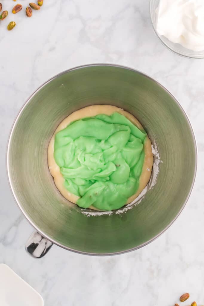 pistachio pudding mixture added to cream cheese mixture in a mixing bowl