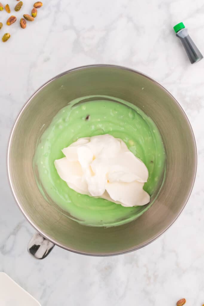 whipped cream added to pistachio mixture in a mixing bowl