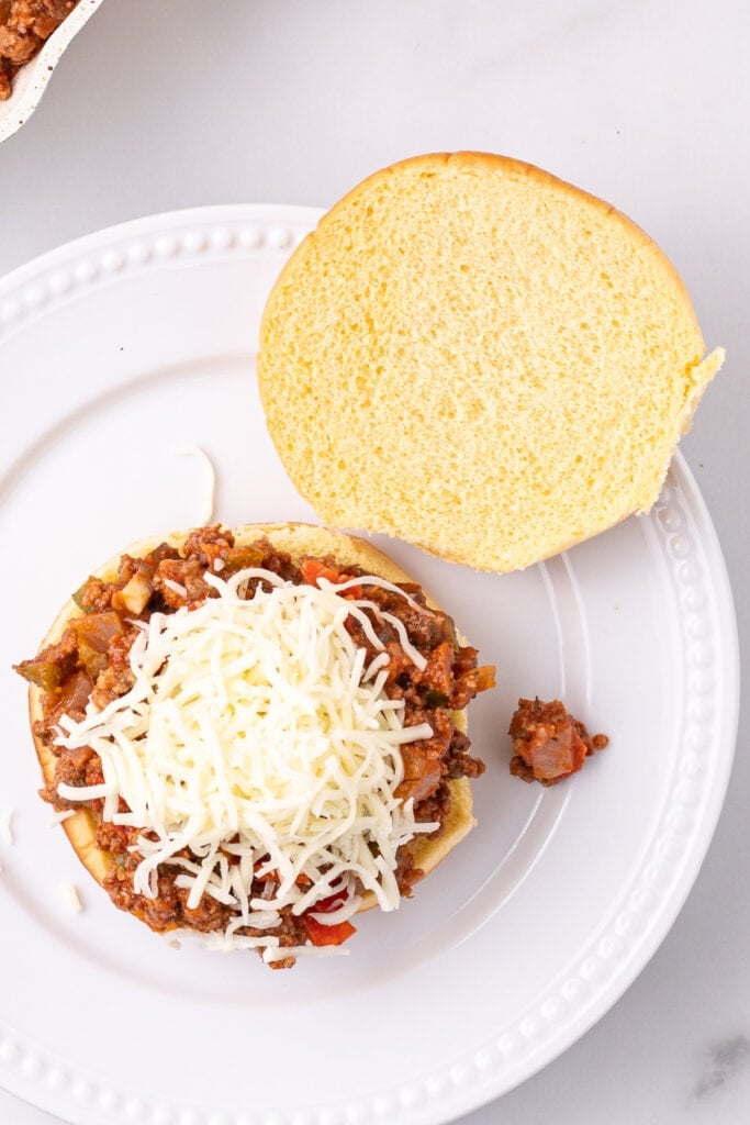 shredded mozzarella cheese added on top of Pizza Sloppy Joes filling on a hamburger bun