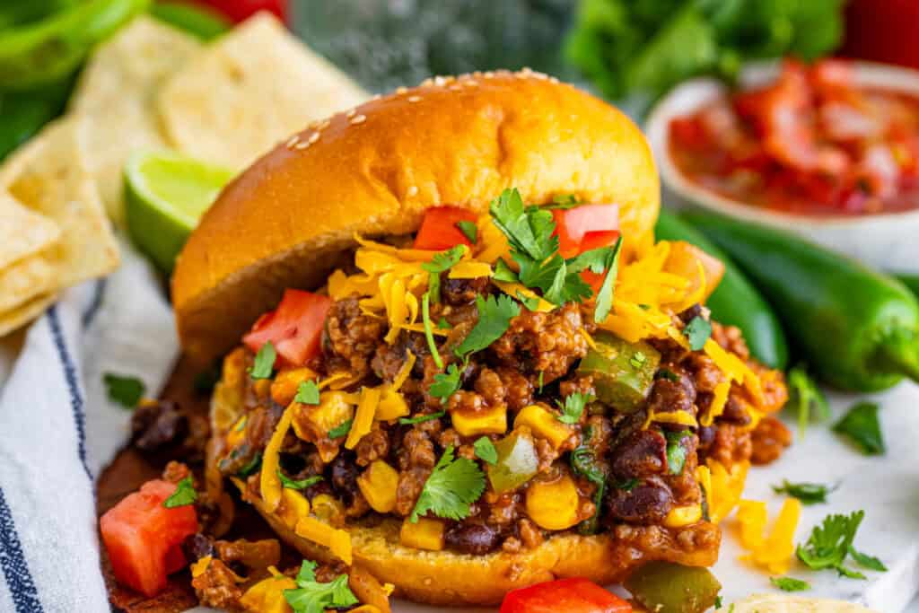 close up of Taco Sloppy Joes sandwich with ground beef, black beans, corn, cheese, and cilantro on a bun