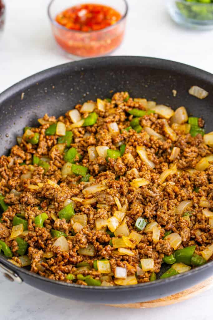 seasoned ground beef with onions and peppers cooking in skillet for Taco Sloppy Joes