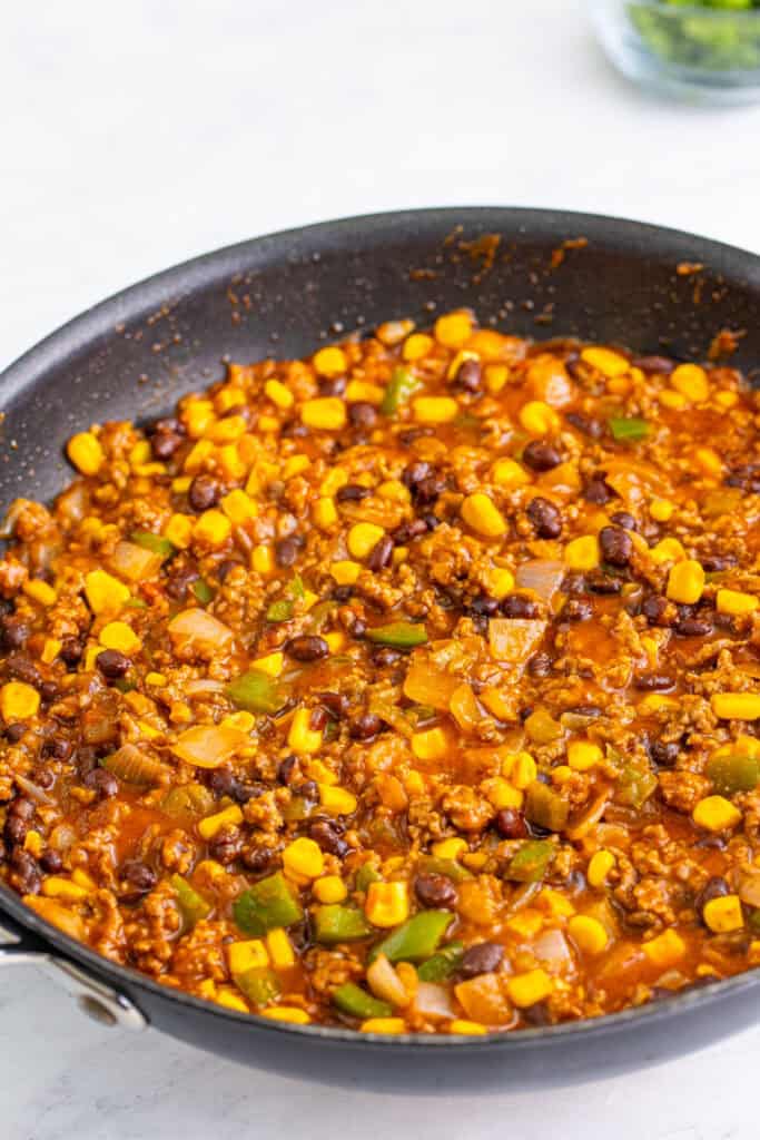 Taco Sloppy Joes mixture simmering in skillet with beans, corn, and sauce