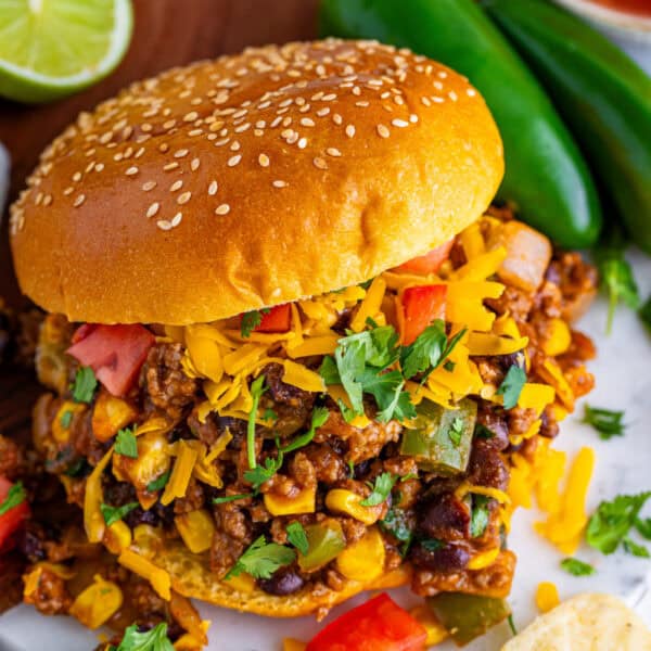 square image of Taco Sloppy Joes sandwich with ground beef, black beans, corn, cheese, and cilantro on a bun