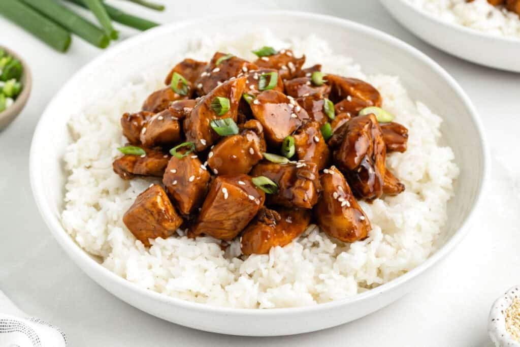 Close-up of Chicken Teriyaki over white rice with sesame seeds and green onions