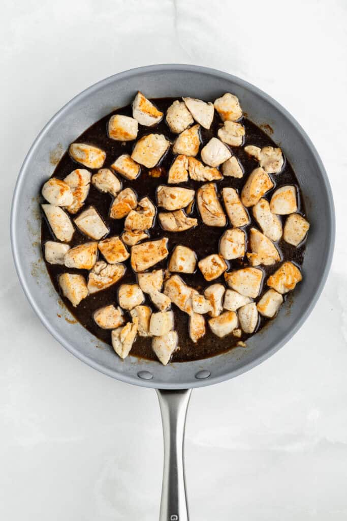 Chicken pieces in a skillet with homemade teriyaki sauce before simmering