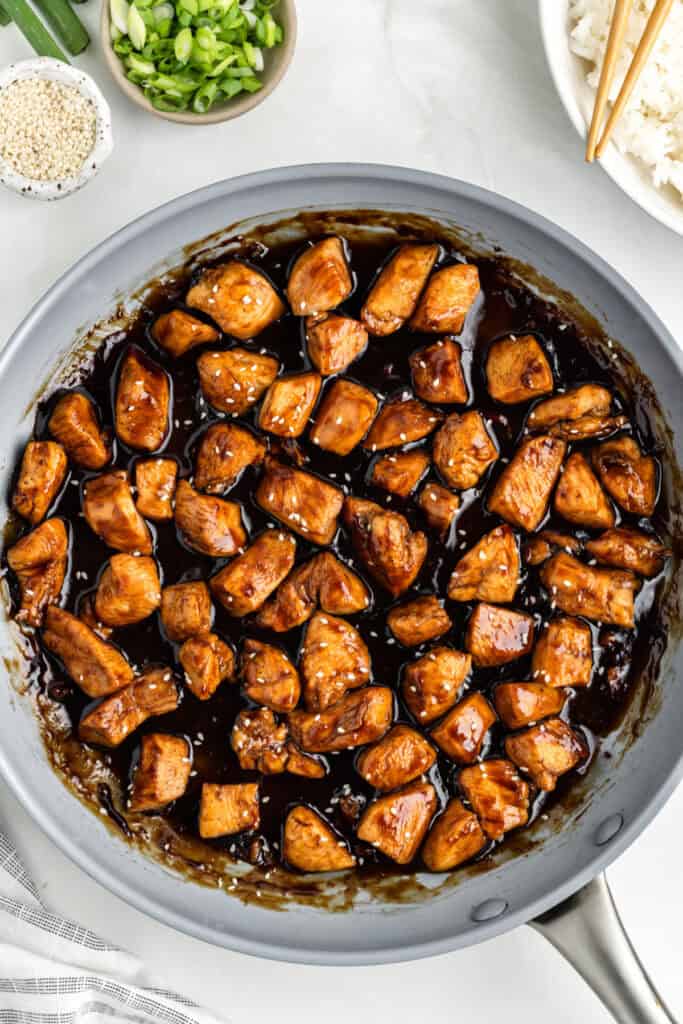 Chicken Teriyaki in a skillet topped with sesame seeds and green onions