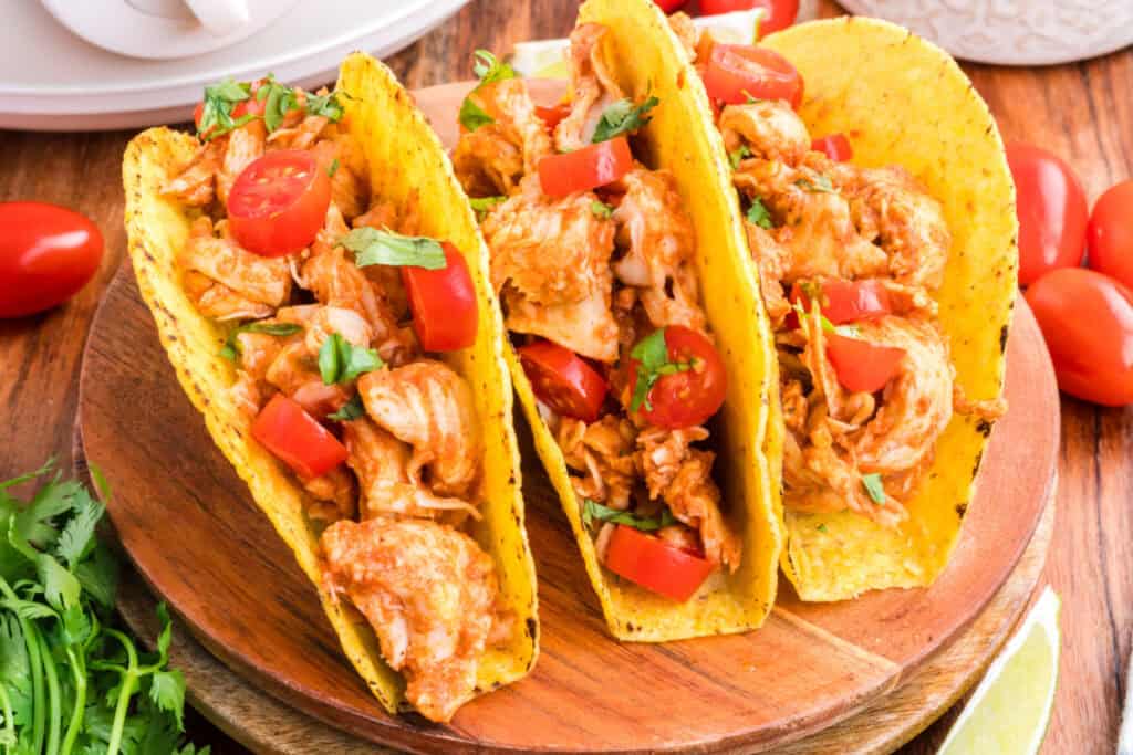 Close-up of Crockpot Shredded Chicken Tacos filled with shredded chicken, tomatoes, and cilantro
