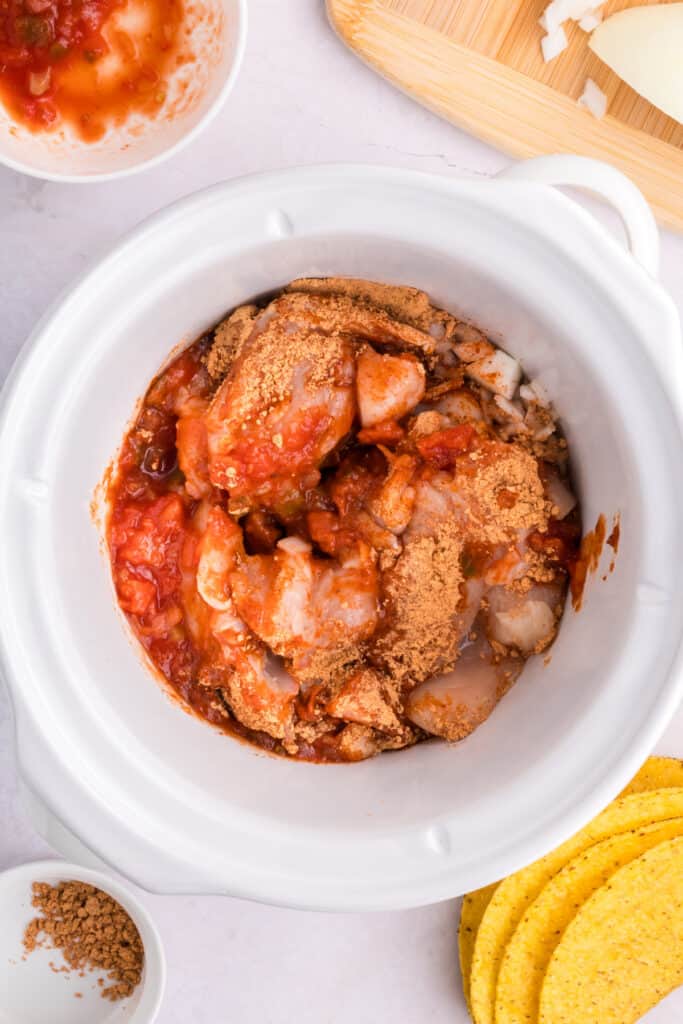 Ingredients mixed together in the slow cooker before cooking Crockpot Shredded Chicken Tacos