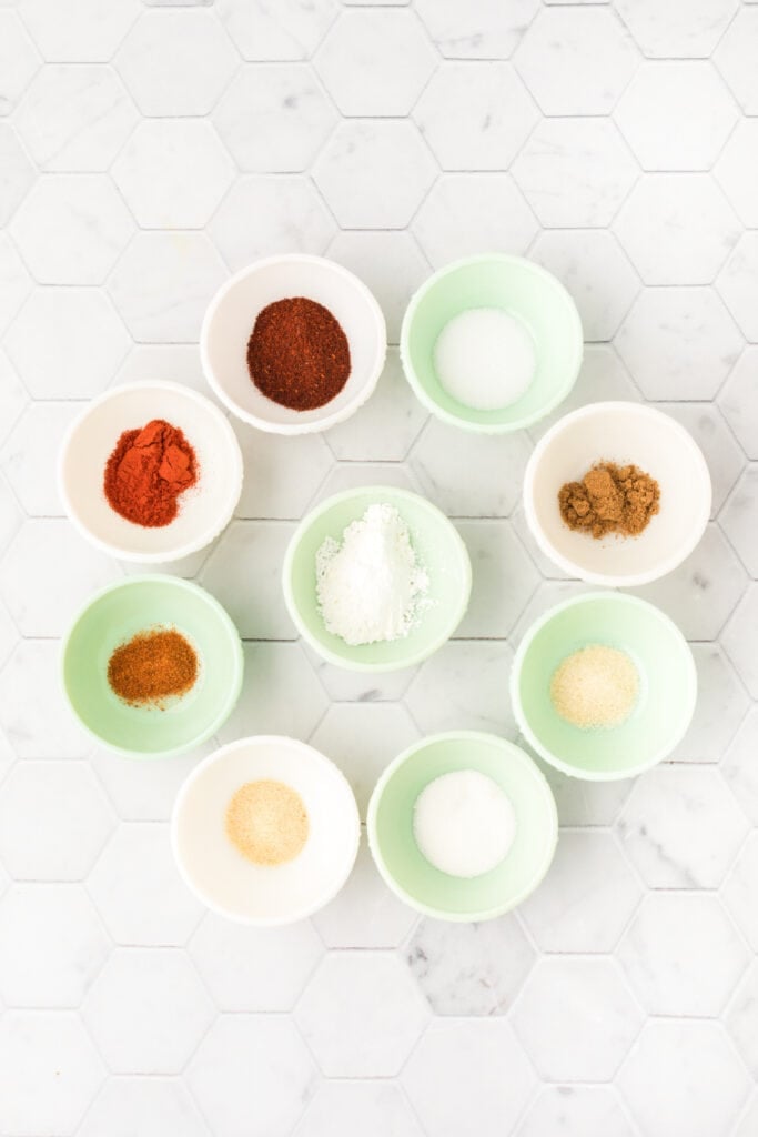 Ingredients for Homemade Fajita Seasoning measured in small bowls on a white hexagon tile surface